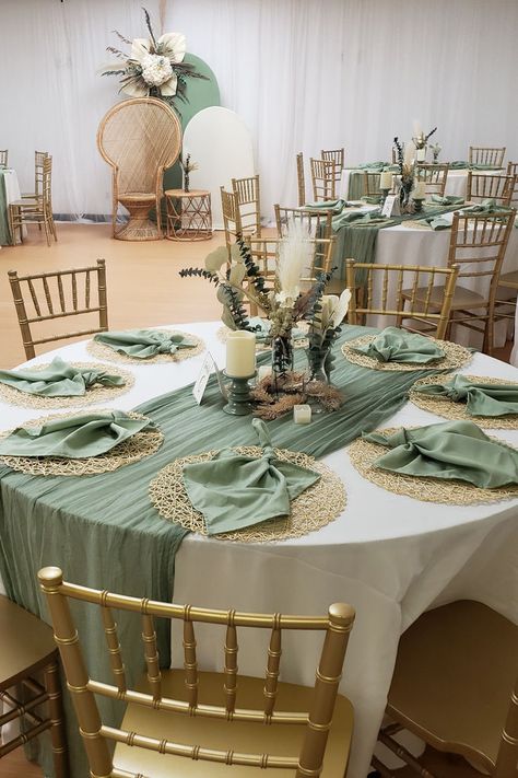 Embrace rustic charm at your event tables. White tablecloths and sage green table runners create a serene base with gold woven placemats and stylishly folded sage green napkins on top. The center hosts candles in themed holders, surrounded by rustic flower arrangements. A Chiara stand backdrop, draped in white and sage green spandex, showcases a boho-themed flower arrangement, completing the rustic allure for an enchanting celebration. 🌿✨ #RusticStyle #EventDecor Rustic Event Decor, Sage Green Napkins, Green Table Runners, Sage Green Table, Rustic Flower Arrangements, White Tablecloths, Event Tables, Flowers Candles, Green Napkins