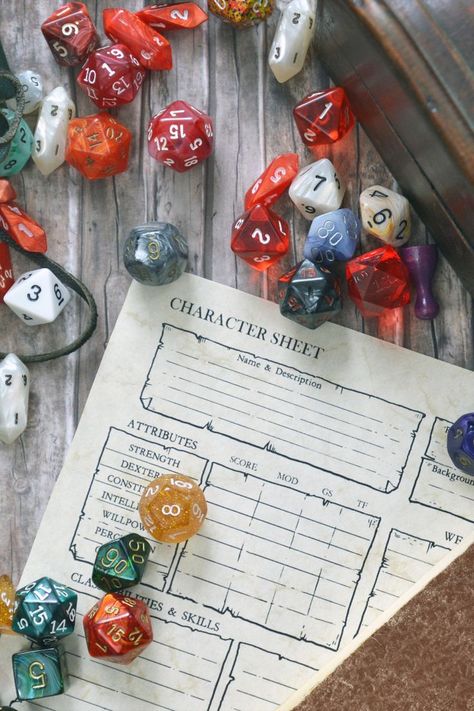 overhead shot of a table with Dungeons & Dragons character sheets, colourful 20-sided role-playing gaming dice and game pieces scattered around the paper. Fantasy Name Generator, D Name, Dm Screen, Embrace The Chaos, Dungeons And Dragons Dice, Location Inspiration, Name Generator, Fantasy Setting, Game Dice