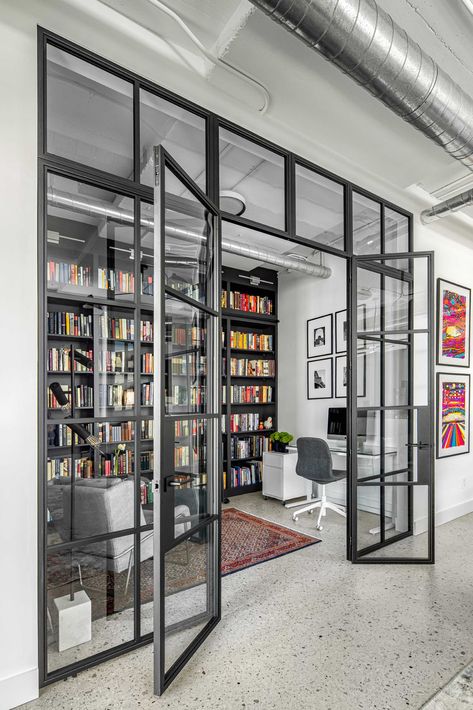 A modern home library enclosed behind a glass wall, has custom black shelving and a ladder to reach the upper shelves. Library And Office Room, Glass Study Room, Shared Office Space Ideas Home, Office Divider Ideas, Industrial Room Divider, Home Gallery Design, Office Extension, Modern Loft Apartment, Cinnamon Bites