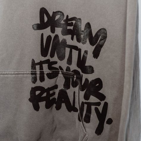 DREAM UNTIL IT'S YOUR REALITY- the perfect streetwear hoodie. This one is for the dreamers. This shirt is made from a hand written design made by Ginger and printed over the front pocket for more of a unique, statement piece. The stark black ink on the light faded grey color makes it the perfect moody piece for your loungewear essentials. Size up for more of an oversized look Product Details: Boxy, oversized fit with dropped shouldersHeavy weight, 7.1 oz100% carded cottonWide neck ribbing with t Streetwear Clothing Design Ideas, Dream Until It’s Your Reality, Hoodie Streetwear Design, Black Hoodie Design Ideas, Unique Hoodies Design, Creative Hoodie Design Ideas, Diy Hoodie Design, Hoodie Print Ideas, Aesthetic Hoodie Design