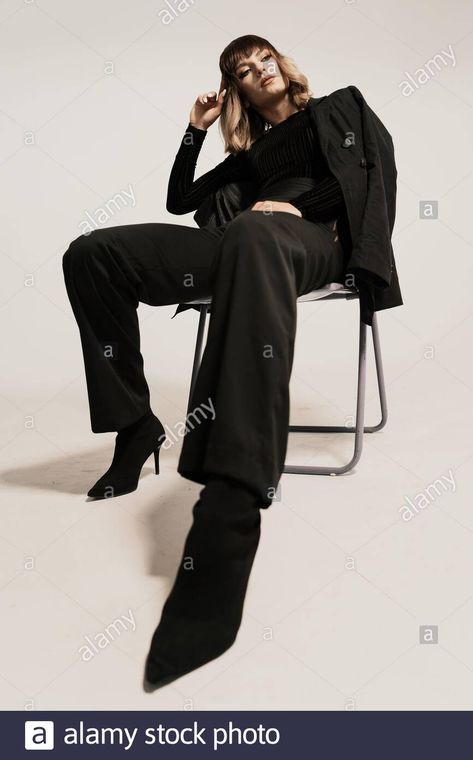 Download this stock image: Portrait beautiful woman with attitude sitting on a chair wearing black clothes posing on white background looking at the camera - 2BGECA9 from Alamy's library of millions of high resolution stock photos, illustrations and vectors. Sitting Down On Chair Poses, Woman Sitting On A Chair Pose Reference, Pose Reference Photo Sitting Chair, Poses On The Chair, Power Sitting Pose, Person Sitting In Chair Pose, High Fashion Chair Poses, Powerful Sitting Pose, Poses For Sitting On A Chair