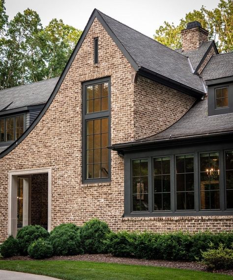 An exposed brick wall match with any home style. Like the picture above, by using exposed brick walls, it gives the exterior of the house look aesthetic. Combine it with black window trim for a more cohesive look. Exposed Brick Wall from @castlehomes #brick #brickhomeexterior #classichomeexterior #homeexterior #homeexteriormaterials #timelesshomeexterior Black House With Red Brick, Exterior House Colors With Brick Red, Black Windows Brick House, Copper Porch Roof, Light Brown Brick House Exterior, Dark Exterior House Colors With Brick, Dark Gray Brick House Exterior, Dark Brown Siding Exterior, Brick House With Black Windows