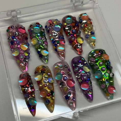 This Junk Nail set is perfect for the maximalist style and Y2K aesthetic! The base is a rainbow of chrome with an assortment of colorful gems and charms. From water pearls to star gems, there's a little bit of everything.  *Since each set is handmade, colors and charm placement may vary from nail to nail and differ slightly from the photos*  Available in shape Medium Stiletto.  This set includes 10 nails fit to your personal sizes in the exact design pictured. Follow instructions listed in perso Nail Art Pictures Ideas, Junk Set Nails, Colorful Y2k Aesthetic, Crazy Colorful Nails, Rainbow Gem Nails, Maximalist Nails Short, Maximalist Nail Art, Christmas Junk Nails, Colorful Star Nails