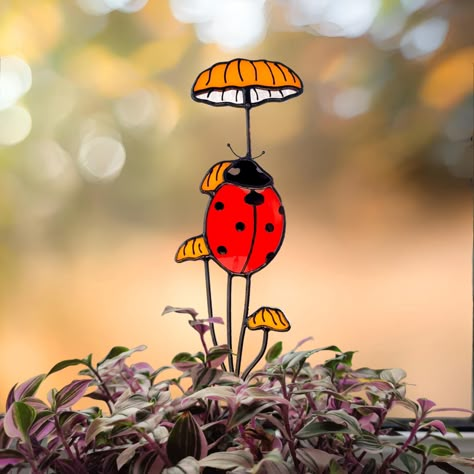 Enhance the charm of your garden with our Handmade Stained Glass Ladybug on Mushroom Plant Stake. This delightful piece combines artistry and function to create a unique plant accessory. The stained glass ladybug perched on the mushroom brings a touch of whimsy to both indoor and outdoor gardens. Perfect for plant lovers and garden enthusiasts, this adorable stake doubles as a decorative window suncatcher. Elevate your plant decor with this handcrafted, versatile addition that adds a dash of per Stained Glass Stakes, Stained Glass Ladybug, Ladybug On Mushroom, Stained Glass Garden Stakes, Stained Glass Plant Stakes, Stained Glass Nature, Stained Glass Garden Art, Stained Glass Spider, Stained Glass Garden