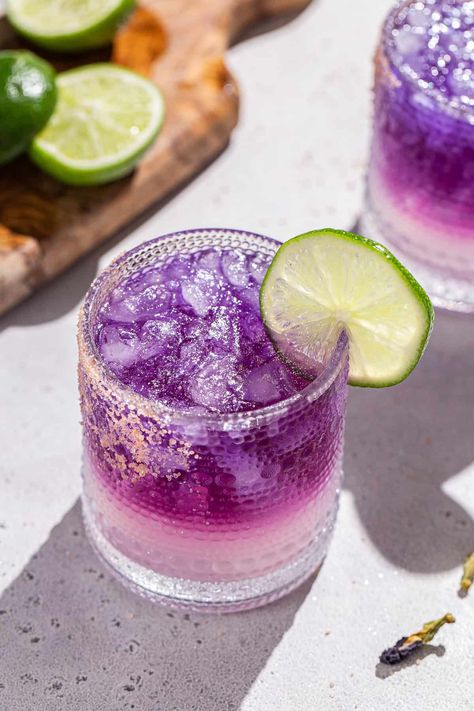 The Galaxy Margarita is as tasty as it is beautiful! Tequila that's naturally colored by butterfly pea flowers is layered on top of a Cointreau and lime base. Edible glitter takes it to the next level! It is a fun galactic spin on a classic margarita. This is the perfect margarita recipe for a girls night, bachelorette or just a night of stargazing! Ginger Shrub Recipe, Summer Happy Hour, Perfect Margarita Recipe, Pink Gin Cocktails, Classic Tequila Cocktails, The Perfect Margarita, Shrub Recipe, Butterfly Pea Flowers, Prickly Pear Margarita