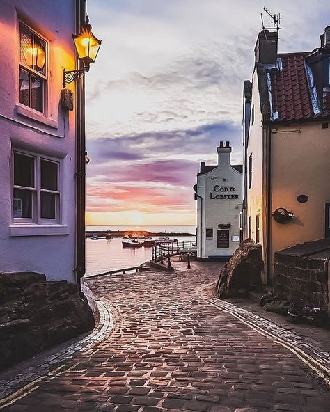 Are you an early morning person...or a night owl? Love that burst of dawn colour as the sun rises over the North Sea at Staithes in gorgeous Yorkshire. Ahhh... a glorious glowing lamp, old cobbles and piping hot fresh fish and chips soaked in lip-smackin' salt and vinegar awaits! That Cod and Lobster pub looks especially inviting too. Love Ireland Landscape Nature, Ireland Landscape, English Village, Holiday Places, England Travel, Beautiful Places To Travel, North Yorkshire, Antalya, Cyprus