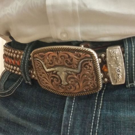 Antiqued Tri-Color Champion Texas Longhorn Belt Buckle - Made in the USA! Free Shipping! Please allow 7-14 days to ship A classically themed Western buckle has a light antiquing covering the silver and yellow gold finishes. A center Champion Texas Longhorn steer gold finished figure sits surrounded by thick flowing filigree. This steer figure differs from our regular steer figure with a notched horn design. A thick edge of rope finishes the buckle design. Standard 1.5 inch belt swivel. Made in the USA! Dimensions: Width: 3.75" Height: 2.625" Length: 0.789" Materials : 99.9% fine silver and 14 karat yellow gold plated over a brass base. Paint. Montana Armor protective finish to prevent tarnish. Warranty : Western and Trophy buckles have a lifetime limited warranty on manufacturing defects w Belt Buckles Western For Women, Cowboy Belt Buckle Aesthetic, Country Belts For Women, Belt Buckle Aesthetic, Belt Buckles Cowgirl, Big Belt Buckle, Country Belt Buckles, Girls Belt Buckles, Western Belts For Women