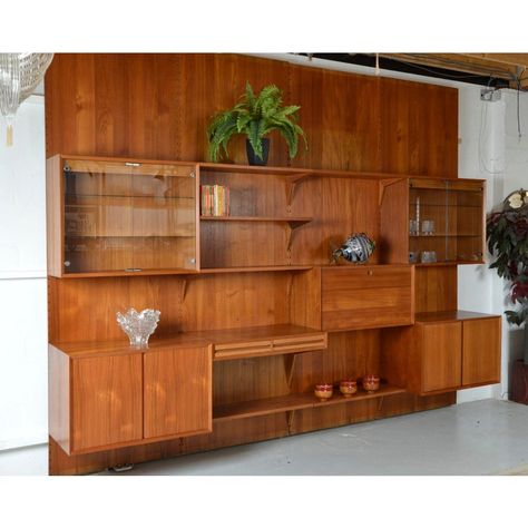 A stunning 1970s four-bay danish teak cado shelving system designed by paul cadovius. These designer shelves are fully modular, allowing an infinite number of combinations and is easily assembled to the panels by dowels and wooden angle brackets.  comprising of four teak backboards measuring over 8-foot tall, these backboards were designed to be cut down to fit the appropriate room height, and these offer easily enough height for most rooms. There are two matching glass fronted cabinets, each wi Mid Century Modern Built In Bar, Midcentury Modern Bookshelf Wall, Living Room With Mini Bar, Mcm Built Ins, Built In Bars In Living Room, 70s Bookshelf, Built In Bar In Living Room, Designer Shelves, Mcm Storage