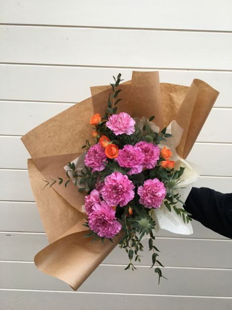 Pink carnations orange roses and thistle and eucalyptus flowers and foliage in a gift wrapped bouquet. Roses And Eucalyptus, Carnation Bouquet, Pink Carnations, Spray Roses, Flower Design, Flower Designs, Floral Wreath, Roses, Spray