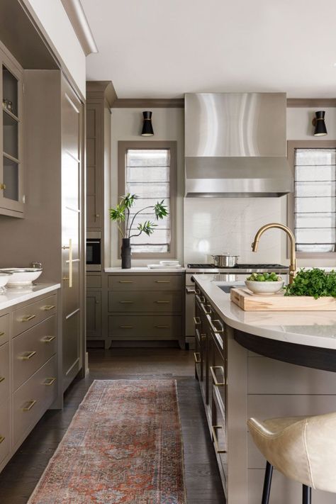 Taupe cabinetry and trim paired with white walls...perfection! This warm kitchen features windows on either side of the hood + shiplap island + paneled in fridge! | Michael Del Piero Taupe Kitchen Cabinets With Wood Island, Green Kitchen Cabinets Wood Trim, Ripe Olive Kitchen Cabinets, Taupe Flat Panel Kitchen Cabinets, Green Shiplap Island Kitchen, Shiplap Island, Hgtv Smart Home 2022, Colored Cabinets, White Built Ins