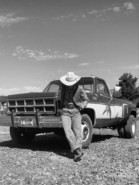 a cowboy is leaning against the front bumper of a vintage gmc truck. the photo is in black and white. they are looking down at the ground, wearing a large hat, a checkered shirt, a vest, and boots. Cowboy Boots Aesthetic, Ranch Photography, Cowboy Photography, Cowboy Ranch, Cowboy Romance, Cowboy Aesthetic, Film Vintage, Wild West Cowboys, Vintage Cowboy Boots