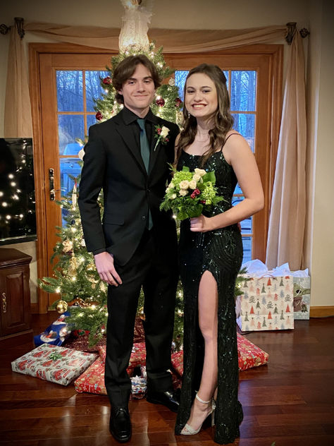 A young couple wearing formalwear posing in front of a Christmas tree Black Suit With Green Tie, Black Suit Green Tie, Suit With Green Tie, Men's Black Suit, Formal Inspiration, Forest Green Dresses, Prom Suit, Black Suit Men, Prom Suits