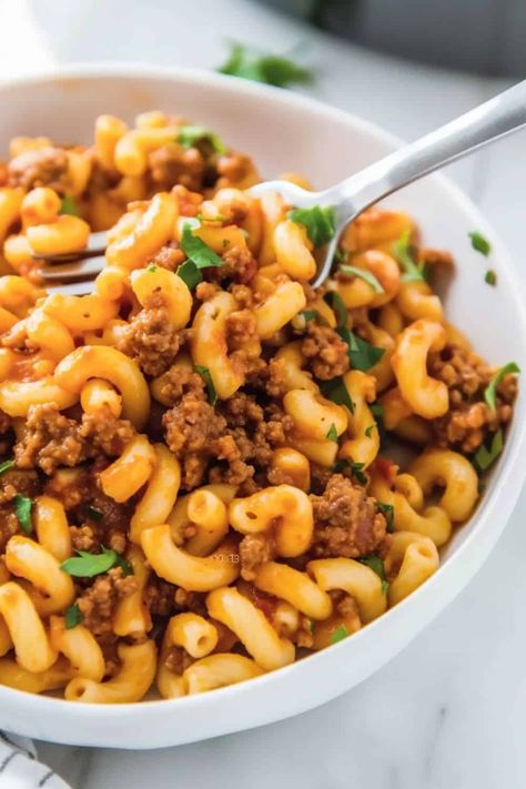 Close-up image of Beefaroni, highlighting the glossy tomato sauce coating the macaroni and ground beef, with specks of Italian seasoning visible, served in a deep dish with a fork on the side, on a simple kitchen tablecloth. Kids Lunch Ideas For Home, Lunch Ideas For Home, Meat Recipes Easy, Meaty Pasta, Cooking Macaroni, Classic Family Meals, Beefaroni Recipe, Easy Quick Dinner, Pasta With Meat Sauce