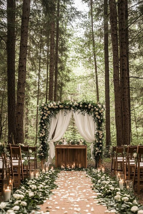 Forest wedding decor altar wooden arch with canopy sheers greenery and white roses the altar table with candles in front there are rows of chairs. Let your big day become a magical woodland affair with these enchanting forest wedding ideas that’ll make your guests feel like they’ve stepped into a fairy tale. Wedding Venue In The Woods, Outdoor Wedding Altar, Elegant Forest Wedding, Wedding Forest Green, Fairy Forest Wedding, Outdoor Wedding Altars, Forest Wedding Theme, Dnd Wedding, Mystical Wedding