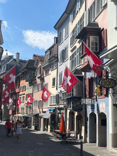 Switzerland Zurich, Switzerland City Aesthetic, Zurich Switzerland Aesthetic Summer, Switzerland Flag Aesthetic, Switzerland Town, Zurich Switzerland Shopping, Old Town Zurich Switzerland, Zurich Old Town, Switzerland Flag