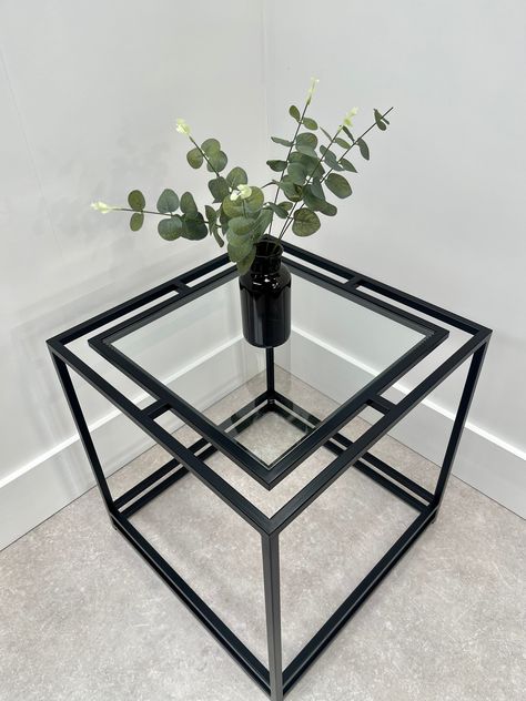 This contemporary metal and glass side table features a modest metal frame supporting a floating clear glass top. It's eye catching design makes it a real focal point and the perfect place to display your favourite lamp or ornaments. Discover more from our Thea collection. Item Specifics W53cm x D53cm x H55cm 15mm square tube Toughened Glass Frame fully assembled Made in Britain. Delivery Order now for delivery in 1/2 weeks! Need a specific size? We can customise our products to suit the size an Steel Frame Furniture, Glass Side Table, Metal Furniture Design, Glass Side Tables, Black Side Table, Metal Side Table, Glass Frame, Steel Table, Creative Furniture