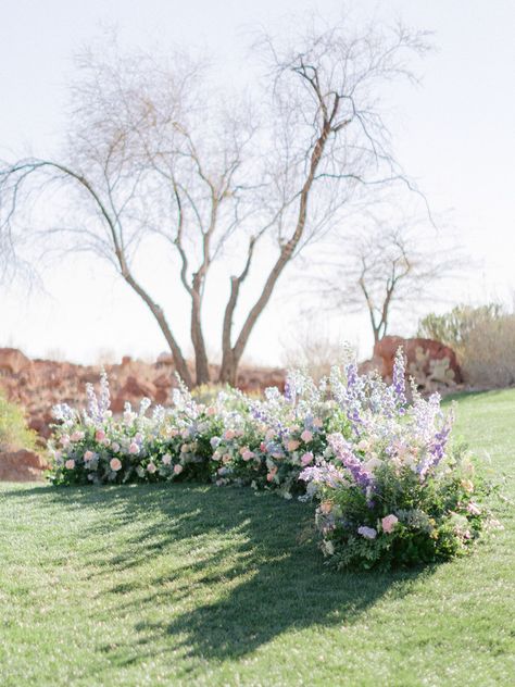 Grounded floral arch in colorful shades of purple, pink, peach, and blue. Grounded Floral Arches, Ground Florals, Wooden Arch, Ceremony Flowers, Floral Arch, Lavender Blue, Pink Peach, Wedding Arch, Shades Of Purple