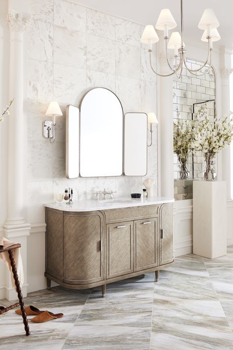 Parisian inspired bathroom design idea. Woodgrain bathroom vanity with curved edges and marble countertop, marble tile floor with warm veining, nickel finish trifold mirror, wall sconces with matching chandelier light. Classic Parisian Interior, Contemporary Tile, Linen Cabinets, Ann Sacks, Metal Bathroom, Medicine Cabinets, Vanity Design, Bathroom Vanity Base, Wall Mount Faucet