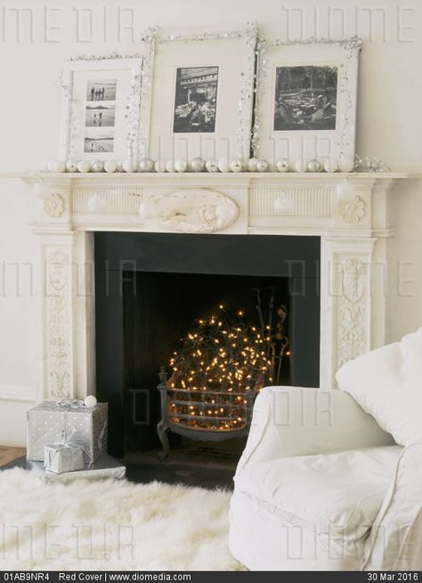 STOCK IMAGE - A detail of a traditional fireplace decorated for Christmas, black hearth with fairy lights, photographs trimmed with tinsel, silver and white baubles placed on the mantelpiece, presents, by www.DIOMEDIA.com Fireplace Filler, Empty Fireplace Ideas, Black Hearth, Small Basement Design, Farmhouse Mantle Decor, Country Fireplace, Craftsman Fireplace, Faux Fireplace Mantels, White Baubles