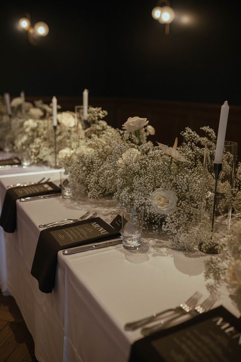 To bring their modern Art Deco reception to life, the bride and groom chose timeless black and white elements, as well as clear architectural details including their seating chart with white printed lettering in a variety of contemporary fonts. Black and white linens were adorned with trendy baby's breath centerpieces accented by full white roses. #weddingdecor #weddingideas #babysbreath December Wedding Black And White, Trendy Wedding Centerpieces, Black And White Wedding Dinner, White Wedding Black Accents, Black White And Beige Wedding Decor, Black And White Bride And Groom, Black Tie Wedding Reception Centerpieces, No Flower Centerpieces Wedding, Wedding Table Decorations Black And White