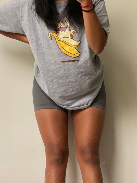 Evelyn wearing a grey oversized t shirt with a smiling banana in the middle and dark grey biker shorts. Big Tee And Shorts Outfit, Oversized Tee Gym Outfit, Big Shirt Gym Outfit, Gray Biker Shorts Outfit, Oversized Gym Outfit, Tshirt And Shorts Outfit, Shorts Gym Outfit, Cycling Shorts Outfit, Gym Shorts Outfit