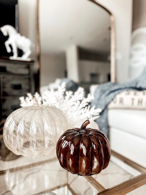 Two glass pumpkins and a glass pumpkin candle sit on a gold and glass coffee table next to a faux coral decor object. Beige Fall Decor, Fall Decor 2024, Autumn Apartment, Glass Pumpkin Decor, Target Glass, Autumn Interiors, Fall Apartment, Apartment Therapy Inspired Decor, Glass Decor Ideas