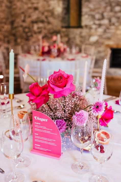 Neon pink vibrant floral table centrepiece of roses and gypsophila with twisted candles and pomegranate fruit decor Floral Theme Table Decor, Pink Table Flowers Wedding, Fushia Table Setting, Modern Pink Tablescape, Pink Flower Table Decorations, All Pink Floral Centerpieces, Wedding Table Decorations Round Tables Pink, Bright Pink Wedding Centerpieces, Pink Table Flowers