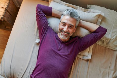 Mature man smiling while lying on his bed wearing pajamas with his hands behind on his head in the early morning Guy Laying In Bed, Figurative Poses, Bed Selfie, Man Smiling, Men Lie, Laying In Bed, Smiling Man, Woman Standing, Guy Pictures