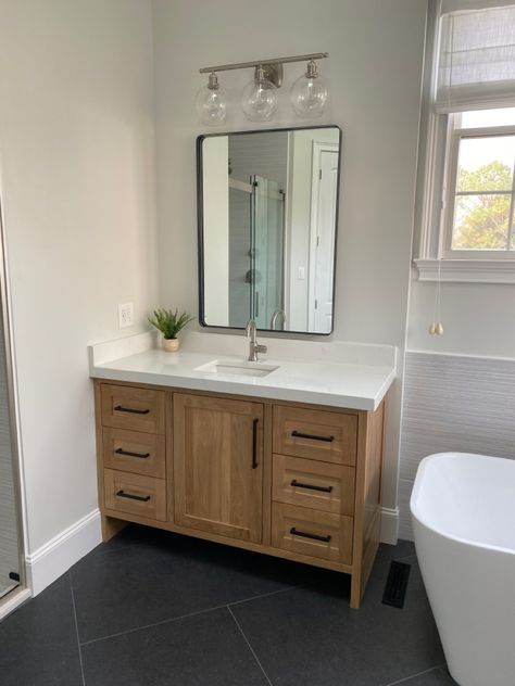 White oak cabinets with bianco aspen quartz. 24x48 tiles in herringbone pattern Oak Wood Vanity Bathroom, White Oak Cabinet Bathroom, Oak Vanity Black Hardware, White Bathroom With Wood Cabinets, Bathroom White Oak Cabinets, Natural Wood Bathroom Vanity With Dark Floors, Wood Cabinets Master Bath, Natural Wood Cabinets Bathroom, Bathroom Remodel With Wood Vanity