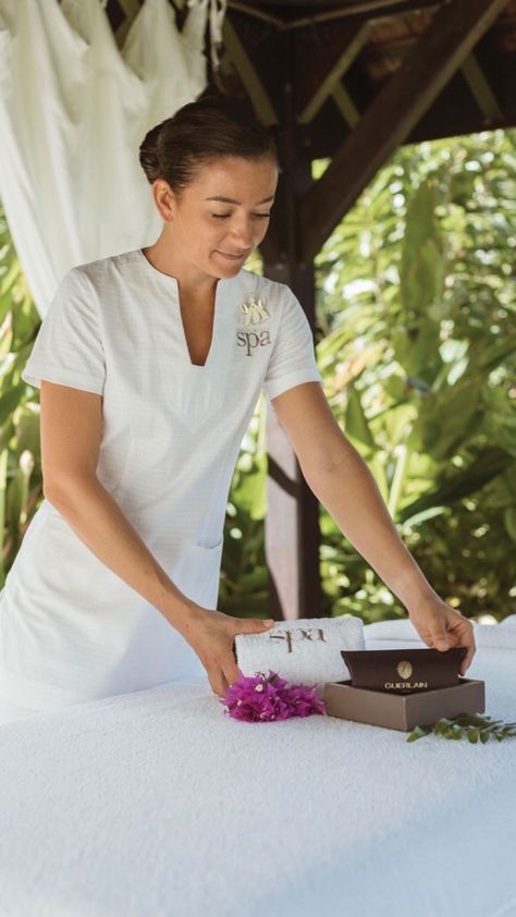 A spa therapist wearing a custom embroidered white spa tunic and spa trousers. Spa Therapist Uniform, Massage Therapist Uniform Ideas, Spa Staff Photoshoot Ideas, Spa Uniform Ideas, Massage Therapist Outfit, Resort Uniform, Massage Beds, Spa Wear, Hotel Uniforms