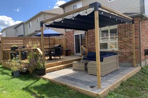 Their raised deck is completed with a wooden privacy fence and a banister that leads into a cozy lounge area. #retractableshade #outdoorliving #retractablecanopy #backyardpatio #retractablepergola #sunprotection #outdoorstructures #moderndesign #backyardretreat #rainprotection #waterproofcanopy #backyardrenovations #exteriordesign #backyardpatiodesign #backyardinspiration #pergoladesign #backyarddeckdesign Toja Grid Pergola Ideas With Roof, Toja Grid Ideas, Deck To Patio Transition Ideas, Toja Grid Pergola Ideas, Fence Ideas Privacy, Toja Grid Pergola, Patio 2023, Privacy Screens Outdoor, Privacy Deck