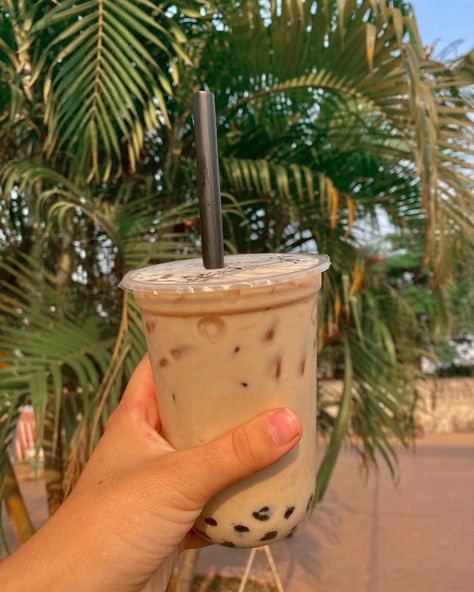 bubble tea being hold by a left hand with a palm tree in the background Boba Tea Aesthetic Pictures, Bubble Tea Aesthetic Instagram, Milk Tea Picture, Tapioca Aesthetic, Boba Milk Tea Aesthetic, Instagram Feed Pictures, Bubble Tea Photo, Tea Food Photography, Aesthetic Boba Tea