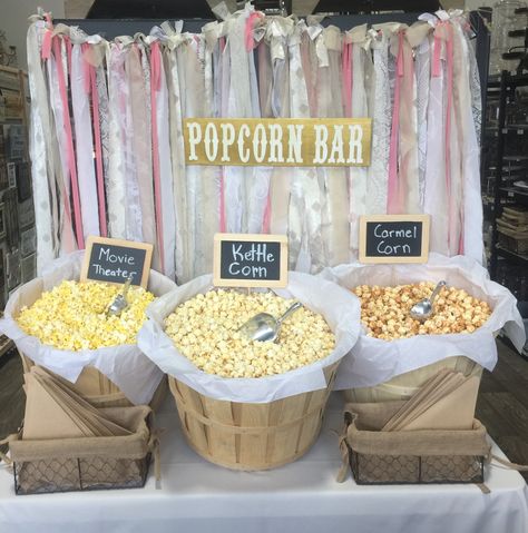 Popcorn bar with bushel baskets and fabric garland backdrop Graduation Popcorn Bar, Graduation Popcorn Bar Ideas, Popcorn And Pretzel Bar Wedding, Diy Popcorn Bar Wedding, Popcorn For Dessert Table, Popcorn Bar Wedding Receptions, Popcorn Bar Containers, Popcorn Cocktail Hour, Wedding Reception Popcorn Bar