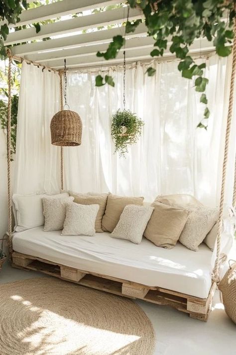 Outdoor Pallet Daybed2 Cozy outdoor lounge area with pallet sofa, cushioned pillows, wicker lampshade, hanging plants, and white curtains. | Sky Rye Design Outdoor Daybed Diy, Wicker Lampshade, Hanging Daybed, Design Balcony, Pallet Daybed, House Location, Pallet Lounge, Diy Daybed, Pallet Cushions