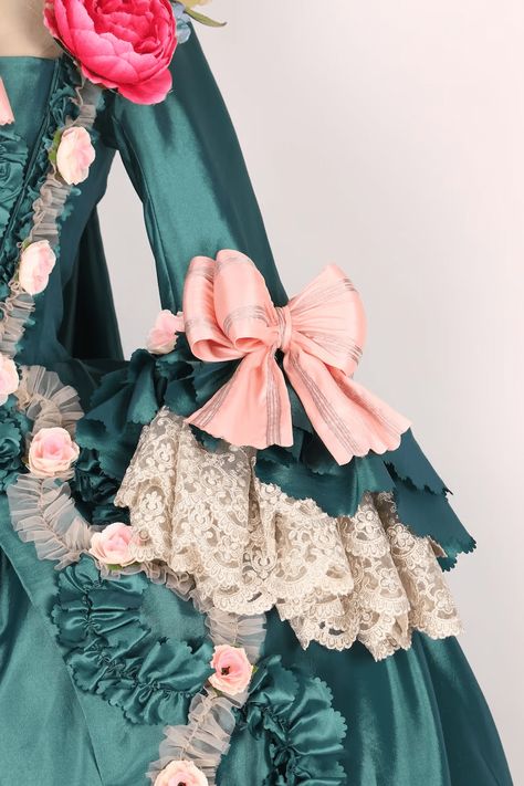 Revel in the grandeur of the past with our Emerald Baroque Style Gown, a resplendent tribute to the rococo and baroque eras. This majestic Victorian Ball Dress, reminiscent of Marie Antoinette's opulent wardrobe, is a symphony of lush emerald green and delicate blush accents. Adorned with artful floral appliqués and ornate lace, each detail is meticulously crafted to evoke the romance of an enchanted garden. The luxurious bows and ruffles are strategically placed to celebrate and flatter a plus-size silhouette, ensuring every curve is graced with elegance. Perfect for grand balls and sophisticated soirees, this gown invites you to partake in the splendor of a regal epoch. Step into a world where every detail is steeped in history, and every moment feels like a page from a fairytale with Wo 1776 Dress, Victorian Ball Dress, Victorian Style Wedding Dress, Historical Outfits, Marie Antoinette Dresses, Georgian Dress, Antique Wedding Dresses, Victorian Ball, Victorian Style Wedding