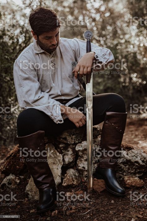 ✅ Young man in historic clothes and with sword sitting on a hill with stones in the forest Stock Photos Poses With Swords Standing, Sitting Swordsman Reference, Man Sitting Pose Reference, Clementine Drawing, Men With Swords, Life Drawing Reference, Male Pose Reference, Ap Studio Art, Graduation Portraits