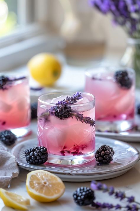 Three glasses of lavender and blackberry lemonade with ice placed on a table with fresh blackberries, lavender sprigs, and a cut lemon. Lavender Drinks, Lavender Lemonade Recipe, Blackberry Mojito, Lavender Drink, Holiday Apps, Blackberry Lavender, Blackberry Drinks, Blackberry Lemonade, Flavored Lemonade