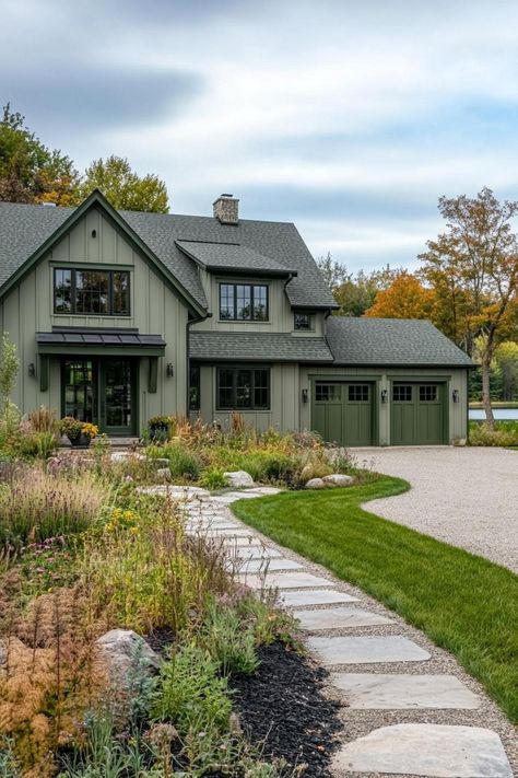 Wide angle view of a large modern farmhouse exterior in greyish pale green board and batten siding slightly darker sage green barn doors and window. Check out all of these dream farmhouses that will have you drooling with rural living fantasies and mooing with joy!