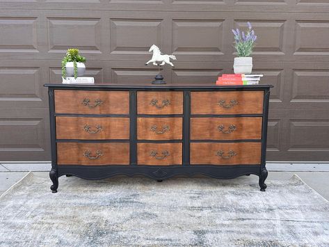 This beautifully refinished French Provincial dresser combines classic elegance with modern flair. The piece features a sophisticated two-tone finish, with the body and trim painted in a rich, velvety black, perfectly complementing the natural wood tones of the drawer fronts and top surface. The original hardware has been meticulously restored, adding a touch of vintage charm. With its elegant curves and solid craftsmanship, this dresser is not only a stunning focal point but also offers ample storage with its six spacious drawers. It's perfect for adding a touch of timeless style to any bedroom, entryway, or living space. Dimensions: 65" L x 32" T x 19" D Condition: Excellent vintage condition, fully restored Materials: Solid wood, metal hardware Finish: Hand-painted black with natural wo Painted Dresser Stained Drawers, Wood Dresser Painted Drawers, Black Dresser Wood Top, Two Tone Wood Furniture, Painted Dresser With Wood Top, Black And Natural Wood Dresser, Two Tone Dresser Painted, Brown Painted Furniture, Black And Wood Furniture