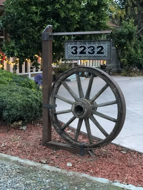 Wagon Wheel Display Ideas, Wagon Wheel Garden Decor, Farmhouse Wagon Wheel Decor, Driveway Address Sign Entrance, Ideas For Wagon Wheels, Wagon Wheels Ideas, Wagon Wheel Driveway Entrance, Rustic Wagon Wheel Decor, Wagon Wheels Landscaping