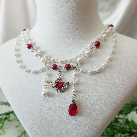 Red and White Beaded Angelcore Necklace with Silver Plated Heart Wing Charm Available in my Etsy shop ExangelsJewelry.etsy.com . . #angelcoreaesthetic #angelcorenecklace #whitebeadedjewelry #grungenecklace #fairycorejewelry #fairycorenecklace #handmadejewelry #beadednecklace #chunkynecklace #princesscorejewelry #princesscoreaesthetic #aestheticgrunge Fairycore Necklace, Grunge Necklace, Red Beaded Bracelet, Red Beaded Necklaces, Pretty Jewelry Necklaces, Diy Jewelry Unique, Pearl Necklace Designs, Tooth Necklace, Polymer Clay Jewelry Diy