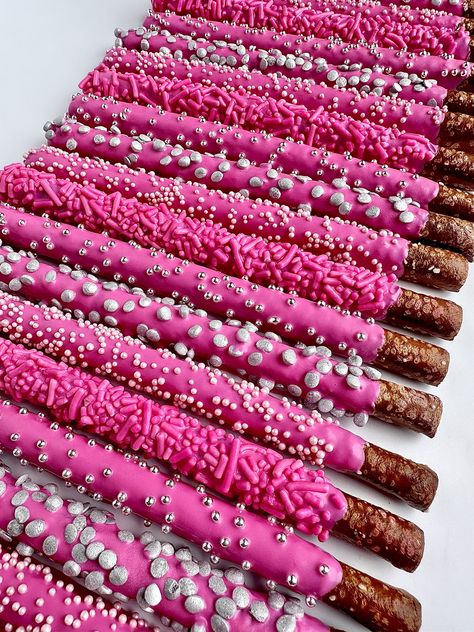 This listing is for 12 chocolate covered pretzels. Each fresh pretzel rod is dipped in creamy hot pink chocolate and decorated with 4 different sprinkles. A perfect addition to a dessert table, a birthday party or shower. So beautiful that all the guests will want one.  Each favor will arrive to you individually wrapped in a clear cellophane sleeve and tied with color coordinating ribbons.  Delightful Chocolates cannot be held responsible for melted chocolate once the package has left our facility. We take great pride in insulating our boxes and packaging with ice sheets if needed PLEASE PURCHASE ICE SHEETS IF YOU LIVE IN A WARM CLIMATE. WE WILL NOT SHIP IF YOU ARE IN TEMPERATURES OF 65 DEGREES OR ABOVE  These confections were crafted in a workplace that also processes peanuts and other tr Pink Silver Themed Birthday Party, Birthday Treats For Parties, Pink Sweet 16 Food, Stuff To Ask For Your 13 Birthday, Pink Birthday Party Drinks, Hot Pink Chocolate Covered Pretzels, Y2k Party Desserts, Barbie Themed Birthday Party Food Ideas, Hot Pink And Black Dessert Table