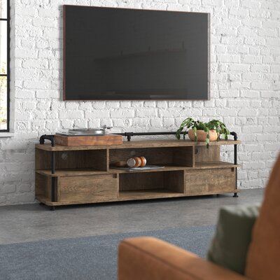 This TV stand blends a distressed wood finish and black waterpipe metal accents to give your living room a traditional industrial look. It's made from engineered wood, with open iron supports around the edges. Two lower-shelf drawers pull out to reveal ample space for books, DVDs, and games. Plus, there are four open cubbies for gaming consoles, media players, and audio equipment. Three separate cable management cutouts help keep your space clutter-free. At 70.87" wide, this stand has plenty of Low Profile Tv Stand, Tv Stand Wayfair, Industrial Tv Stand, Living Tv, Stands Tv, Loft Furniture, Rustic Industrial Decor, Wood Tv Stand, Audio Room