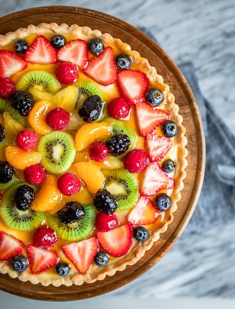 An overhead shot of fresh fruit tart on a wooden stand. Fruit Tart Breakfast, Classic Fruit Tart, La Madeleine Fruit Tart Recipe, Fruit Torte Cake, Whole Foods Fruit Tart Recipe, Custard Fruit Tart Recipe, Best Fruit Tart Recipe, Homemade Fruit Tart, Fruit Tart Pie