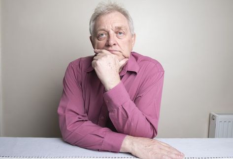 Older man sitting at a table with a ponderous expression as his chin rests on his hand. Hands On Table Pose, Chin Resting On Hand Pose, Successful Habits, Hands On Face, Portrait References, Man Sitting, His Hands, The Fool, How To Know