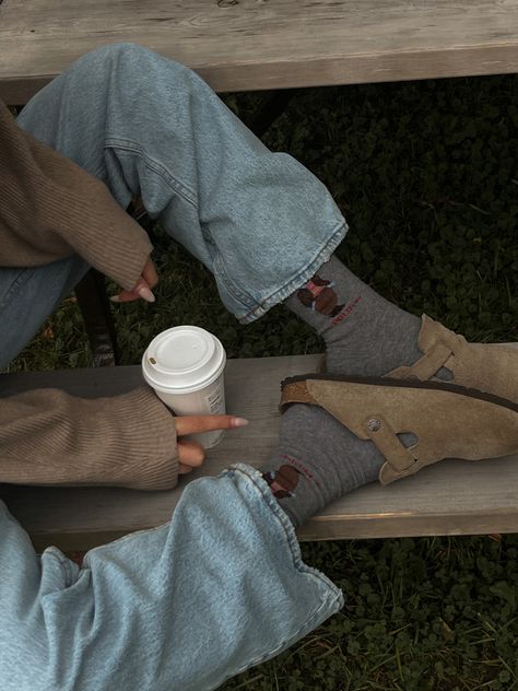 Girl sitting on a park bench in a park with green and fall foliage, holding a Starbucks cup wearing light denim jeans, and Birkenstock Bostons with Polo Ralph Lauren bear socks and a cozy off the shoulder sweater Fall Photo Poses, Coffee Autumn Aesthetic, Polo Bear Socks, Birkenstock Aesthetic, Potato Shoes, Clog Outfit, Boston Soft Footbed, Bear Socks, Coffee Photo