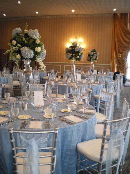 light blue wedding theme- light blue table linens, blue accents in the flower centerpieces, and light blue tulle on silver chairs Sky Blue And Silver Wedding, Blue And Silver Wedding Decorations, Blue Quinceanera Theme, Baby Blue Quinceanera, Ice Blue Weddings, Blue And Silver Wedding, Light Blue Quince, Cinderella Quinceanera Themes, Cinderella Wedding Theme