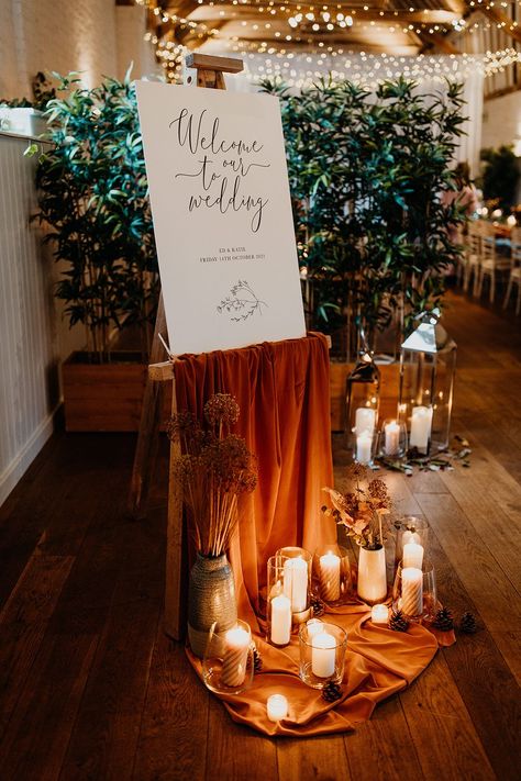 Welcome Sign With Drapery, Ceremony Set Up Indoor, Rust Orange Wedding Decor, Welcome Sign With Candles, Pillar Candles Decor, Orange Rustic Wedding, Wedding Window Decorations, Fall Wedding Welcome Sign, Wedding Welcome Sign Ideas