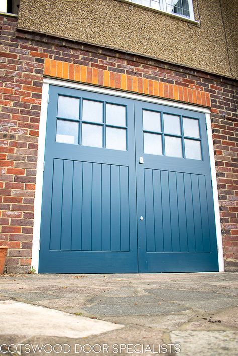 Handsome 1930s wooden garage doors painted in rich Farrow and Ball Hague blue. The traditional side hinged doors feature vertical tongue and groove style panelling and textured obscure glass. Our experienced carpenters have fitted the wooden garage doors with weatherproofing including a head drip bar to protect the doors from rain. Satin chrome door hardware completes the sleek look. Retro Garage Door, 1930s Garage Door, Side Hinged Garage Doors Uk, Garage Door Colours, Garage Doors Painted, Painted Garage Door, Blue Garage Door, Garage Doors Uk, Farrow And Ball Hague Blue