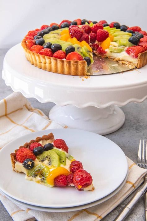 An image of a fresh fruit tart on a white cake stand, with one slice cut and served on a white plate. French Fruit Tart Recipe, French Fruit Tart, Fruit Tart Recipe Easy, Easy Fruit Tart, Fruit Tart Cake, Showstopper Dessert, Fresh Fruit Tart, Fresh Fruit Cake, Fruit Tart Recipe